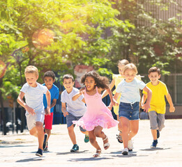 Obraz premium Team of positive kids running in race in the street and laughing outdoors