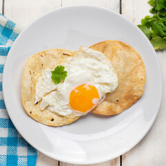 Fried egg and corn tortilla for breakfast on white background