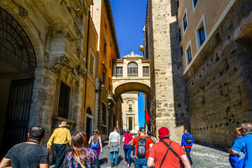 A group of unidentifiable tourists follow a tour guide  through Capitoline Hill and the Portico dii...
