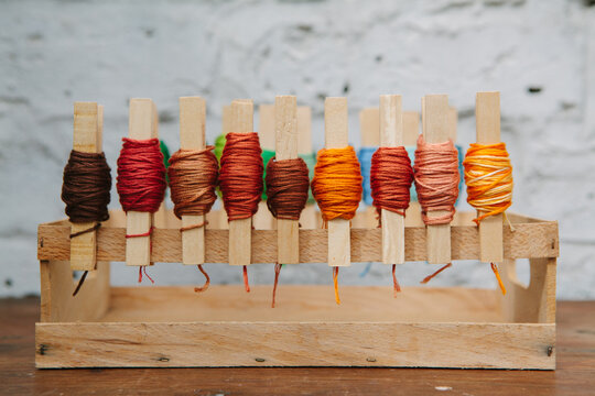 Brown thread organised on pegs on a crate.