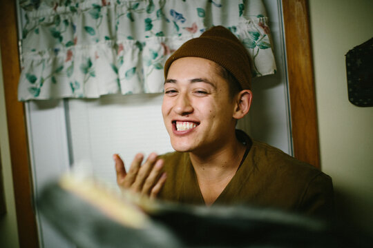 A young boy leaning back against a wall laughs and smiles