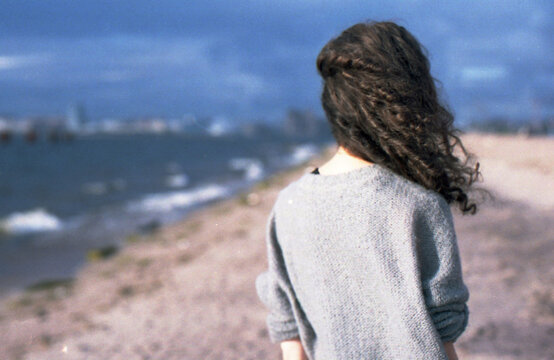 Back veiw of the girl standing in the stormy beach
