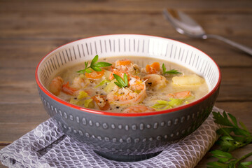 Shrimp prawn chowder with crab meat in a bowl on wooden table. horizontal photo