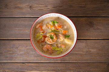 Shrimp prawn chowder with crab meat in a bowl on wooden table. Overhead horizontal photo