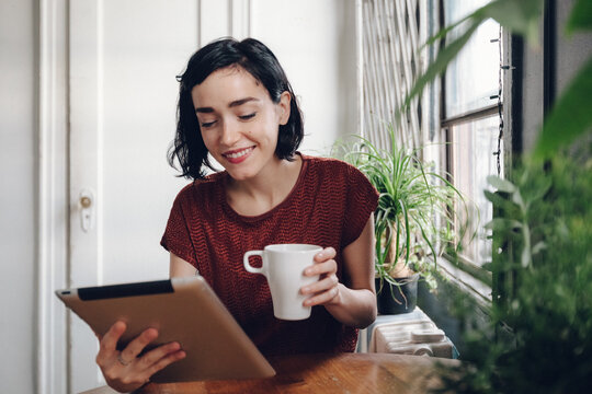Brunette drinking a coffee using a digital tablet