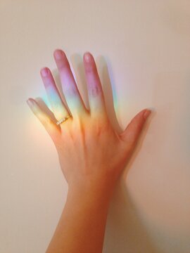 Abstract photograph of a rainbow reflected in a woman's hand.