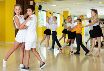 Fototapeta na wymiar Diligent smiling little boys and girls having dancing class in classroom