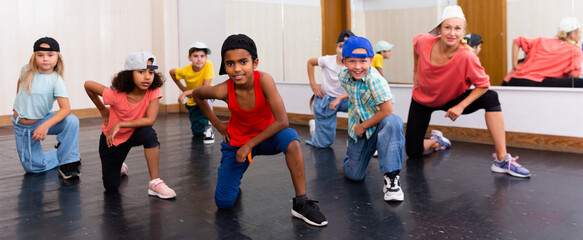 Group of happy tweens with female teacher practicing hip hop in modern dance studio ..