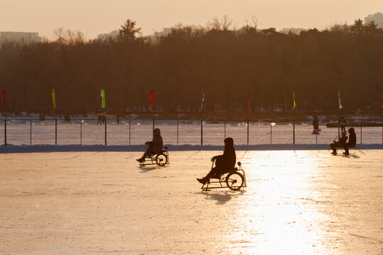 Changchun, Jilin, China - January 30 2021: people riding ice bike, a Chinese traditional entertaining sport, on frozen lake