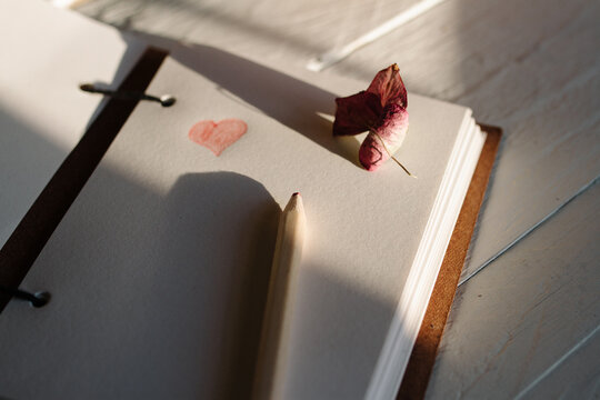 A notebook with a penciled heart, on a sunny desk.