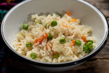 White rice with peas and carrot on wooden