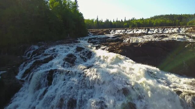 A soothing landscape of nature, namely a beautiful waterfall and forest hills in the distance. Breathtaking views of nature from above