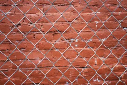 Chain-link fence in front of painted brick wall