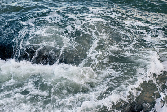 Waves breaking on underwater rocks, creating a small water vortex