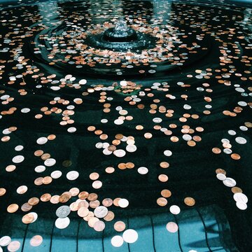 Water in a wishing well with coins scattered at the bottom.