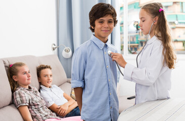 Obraz premium Medic girl with stethoscope with patient boy and children at home