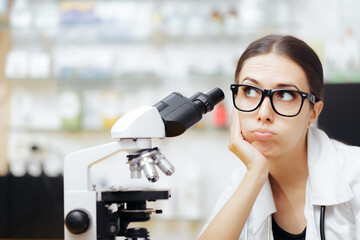 Unhappy Scientist Looking through a Microscope in a Laboratory