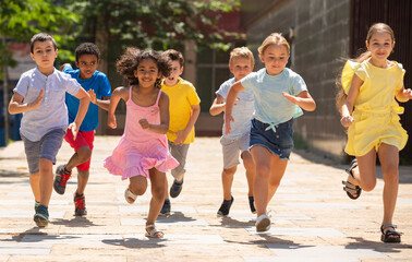 Team of positive kids running in race in the street and laughing outdoors