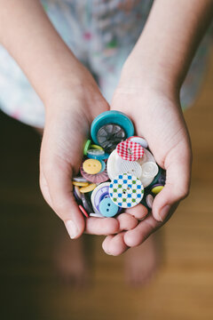 a random collection of buttons in a girls hands, shot from overhead