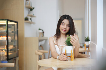 Obraz na płótnie Canvas Portrait of Asian Young happy woman sitting alone in modern coffee shop interior.