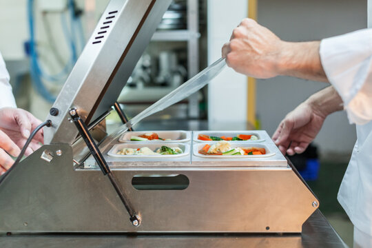 Chefs Shrink Wrappping Food with a Small Packaging Machine