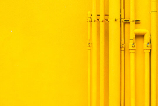 Many yellow pipes arranging in line on yellow wall