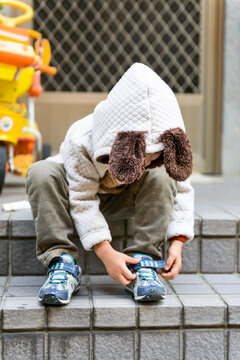 Kid in Autumn Outfit Fixing his Shoes