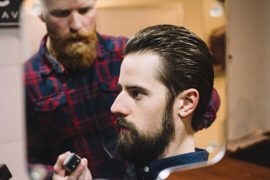 Young man gets beard trim at barber shop