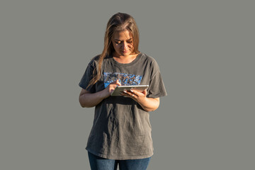 Young woman in a gray t-shirt and jeans with a tablet. Internet and communication, online work and shopping, news and social networks