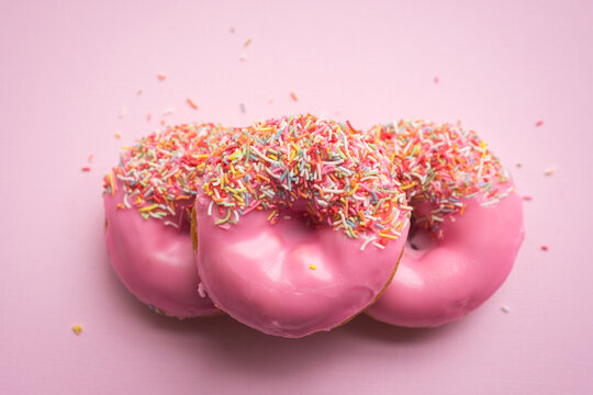 stack of three hot pink donuts on pink background