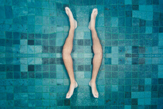 Man's feet underwater reflected of the surface of the swimming pool