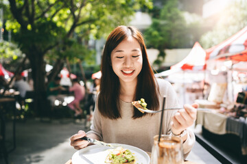 Young adult asian woman eat lunch food at restaurant outdoor on weekend day