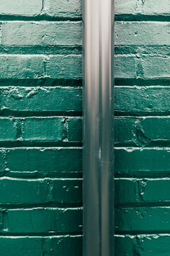 Close up of painted green brick wall and gutter pipe
