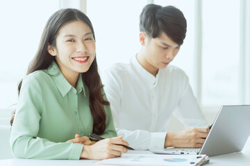 Obraz premium Young Asian business couple working together, completing the assigned work