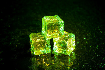 Green ice cubes reflection on black table background.