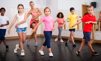 Group of tweens doing dance workout with female coach in classic choreography class..