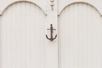 Horizontal detail of a painted white door with bead board details and an anchor door knocker