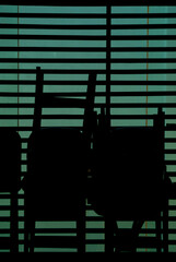 Silhouette of chairs and venetian blinds in a closed restaurant