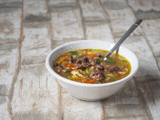 Deep plate of vegetable soup with chicken, serving on a light table