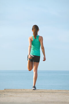 Sport girl doing stretching exercises after run workout on the beach.
