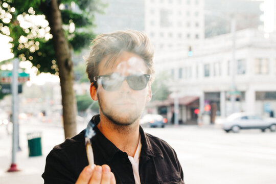 young male smoking in city