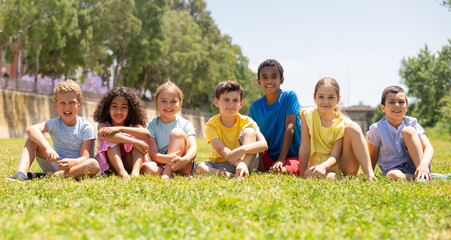 Fototapeta premium Happy children sitting on the green grass on a sunny day