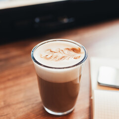 Cup of coffee, notebook at table in cafe. Blurred background