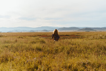 far away among the steppe grass amid the hills the figure of a girl walking into the distance. High quality photo