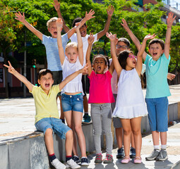 Obraz premium Group of positive children holding hands up and smiling together in park