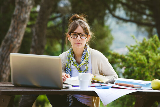 Young student woman with glasses wearing casual clothes and reading on a park.