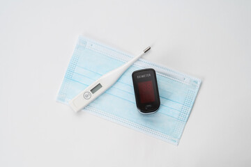 Top view of portable digital fingertip oximeter, surgical mask  and thermometer isolated on white background