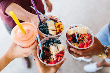 A group of friends holding up their acai bowls together
