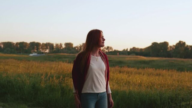 [4k] attractive ginger woman going for a walk in sunset in meadow at river
