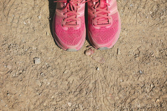 Overhead view of a pink trail shoes on grit background.